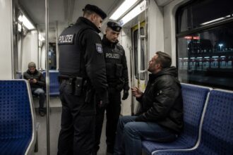 Αστυνομικοί μιλούν σε έναν επιβάτη τρένου σε σταθμό στο Μόναχο