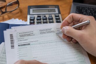 Υπολογιστής τσέπης και έγγραφα φορολογικής δήλωσης πάνω σε γραφείο στη Γερμανία