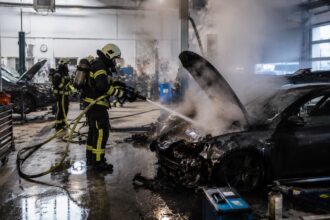 Πυροσβέστες προσπαθούν να σβήσουν πυρκαγιά από ηλεκτρικό αυτοκίνητο μέσα σε μεγάλο συνεργείο της Έσσης.