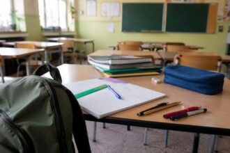 Σχολικά είδη, τετράδια και τσάντα σε γραφείο με φόντο σχολική αίθουσα στη Γερμανία.