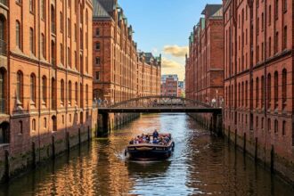 Κανάλι της ιστορικής περιοχής Speicherstadt στο Αμβούργο με πλοιάριο που διασχίζει τα ήρεμα νερά
