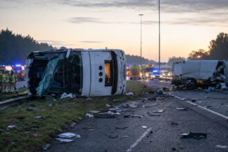 Διασώστες επιχειρούν γύρω από ανετραμμένο λευκό λεωφορείο σε αυτοκινητόδρομο της Ολλανδίας έπειτα από σοβαρό τροχαίο ατύχημα.