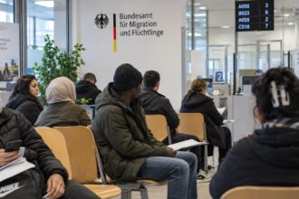 Άνθρωποι περιμένουν σε αίθουσα αναμονής του Ομοσπονδιακού Γραφείου Μετανάστευσης στη Γερμανία