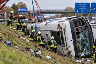 Σκηνή από τη διάσωση στο σημείο του δυστυχήματος στην A96 κοντά στο Buchloe, με πυροσβέστες να ασφαλίζουν το ανεστραμμένο τουριστικό λεωφορείο.