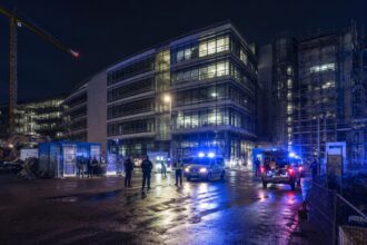 Αστυνομικές δυνάμεις και οχήματα έξω από εργοτάξιο εταιρικού κτιρίου τη νύχτα στο Μόναχο