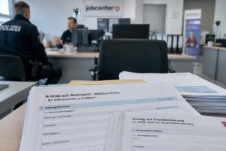 Έντυπα αιτήσεων κοινωνικών επιδομάτων πάνω σε γραφείο γερμανικής δημόσιας υπηρεσίας