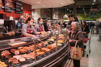 Πελάτες αγοράζουν ζεστό έτοιμο φαγητό από τον μπουφέ ενός γερμανικού σούπερ μάρκετ