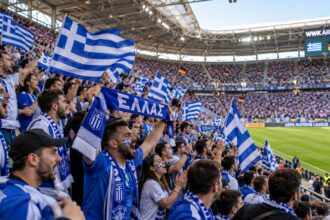 Έλληνες φίλαθλοι στις κερκίδες του γηπέδου στο Άουγκσμπουργκ κρατώντας σημαίες