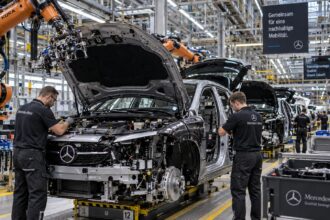 Γραμμή παραγωγής σε εργοστάσιο αυτοκινήτων στη Γερμανία με εργάτες και ρομποτικούς βραχίονες