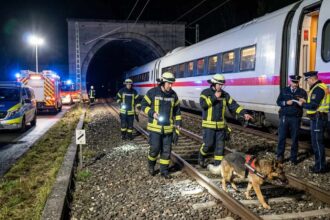 Ένα γερμανικό τρένο ICE σταματημένο τη νύχτα στις ράγες ενώ διασώστες ερευνούν την περιοχή με φακούς