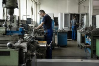 Εργαζόμενοι σε γερμανικό βιομηχανικό εργαστήριο με μηχανήματα παραγωγής, στο πλαίσιο των ιταλικών εξαγορών.