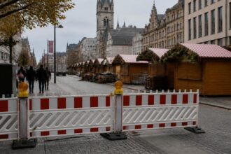 Προστατευτικά εμπόδια μπροστά σε ξύλινους πάγκους χριστουγεννιάτικης αγοράς σε γερμανικό αστικό δρόμο.